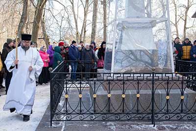 Лития на могиле А. С. Пушкина. На переднем плане священник в белой рясе. За ним стоит группа людей.